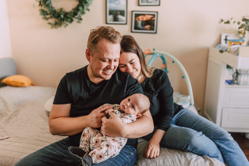 Lachende man en vrouw met baby zittend op bed