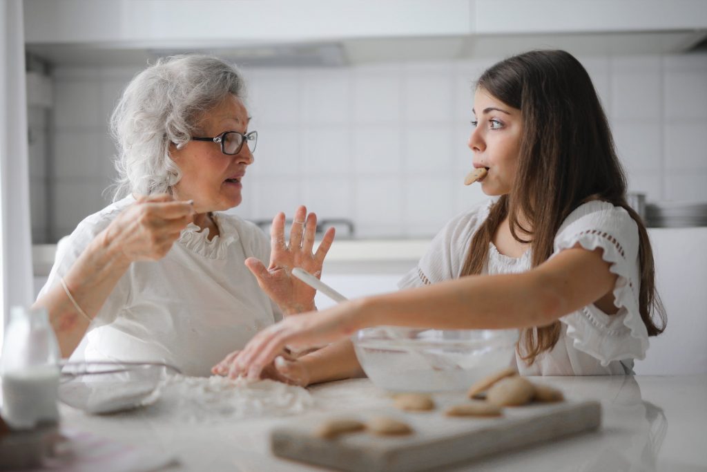 Een oma en kleindochter in witte kleding bakken samen koekjes