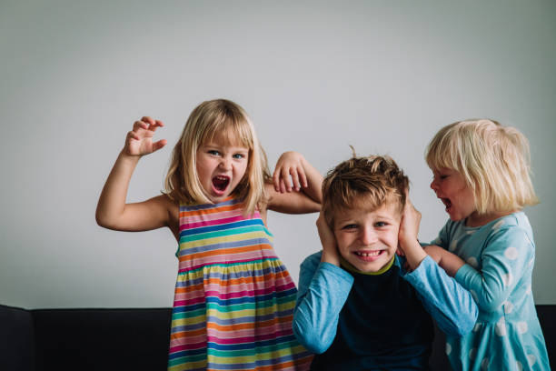 Twee kleine zusjes schreeuwen en hun broer doet zijn handen over zijn oren